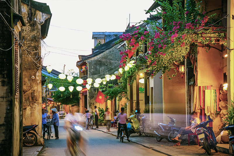 street with flower blossoms and ornate architecture in Hoi An, Vietnam